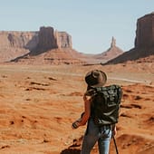 Frau mit Rucksack und Hut schaut auf Felsformation