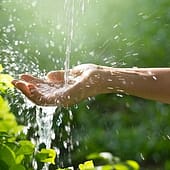 Wasser strömt in Hand einer Frau vor Naturhintergrund