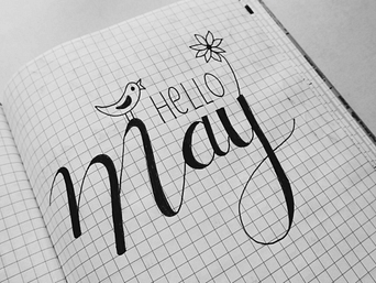 Schriftzug „Hello May“ mit Blüte und Vogel – verspieltes Symbol für das Erwachen und die Freude zu Beltane