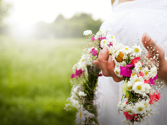 Beltane – Blumenkranz des Segens Hände halten einen Blumenkranz aus weißen und grünen Blüten – Symbol für Segen, Schönheit und Erblühen zu Beltane