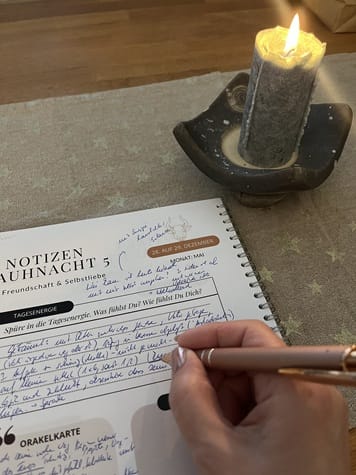 Ein Notizzettel zur 5. Rauhnacht neben einer brennenden Kerze – Reflexion und Dokumentation während der Rauhnächte