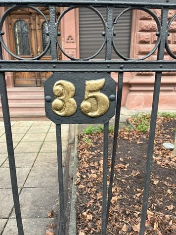 Hausnummer 35 in Gold an einem schmiedeeisernen Zaun