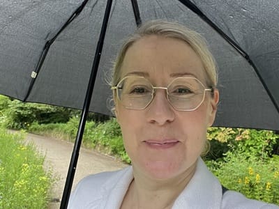 Ich - Jana Engel - beim Spaziergang im Botanischen Garten Frankfurt unter einem Schirm, glücklich und dankbar für ein Jahr ohne Krisen