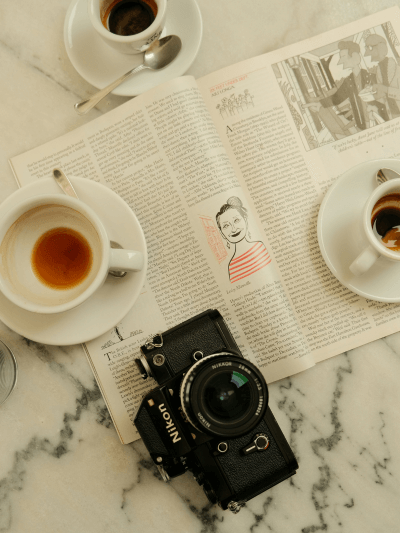 Tisch mit Kamera, Espresso und Zeitung – Spiritualität im Detail und bewusster Alltag