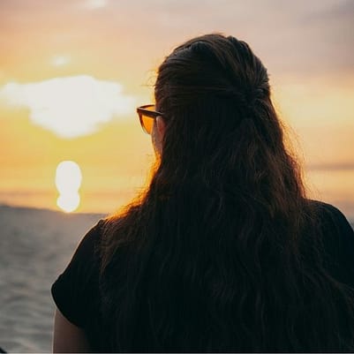 Frau blickt in den goldenen Sonnenaufgang - Symbol für Klarheit, Ausrichtung und bewusste Lebensgestaltung mit Hilfe von Human Design