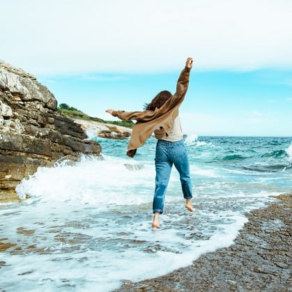 Frau hüpft am felsigen Strand am Meer