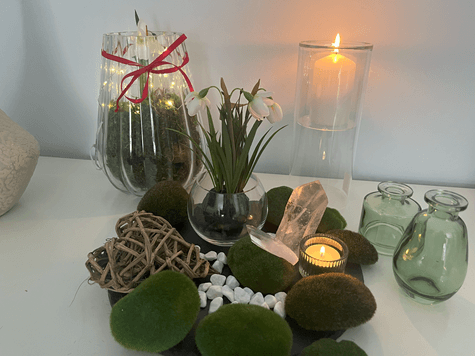 Ein liebevoll gestalteter Brigid-Altar mit Schneeglöckchen, einer weißen Kerze, einem Lichtglas mit Lichterkette, Moos, Bergkristallen und einem Glas Wasser – symbolische Elemente für Imbolc und die Göttin Brigid