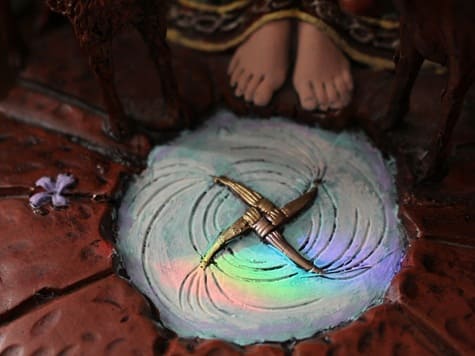 haley-owens-1KxTP7hv6GQ-unsplash Ein goldenes Brigid-Kreuz, eingelassen in den Boden, mit einer Statue im Hintergrund. Das Kreuz symbolisiert das Lebensrad, den ewigen Kreislauf der Natur und die Verbindung von Himmel und Erde. Traditionell wird es zu Imbolc in Räumen angebracht, um Schutz und Segen für das kommende Jahr zu bringen