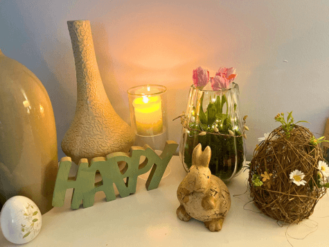 Ein Ostara-Altar mit einem Kerzenlicht, Tulpen, einem Hasen und einem Porzellanei – eine liebevolle Gestaltung zur Feier des Frühlings