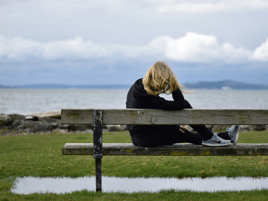 Frau sitzt auf einer Bank und blickt über das Wasser - Symbolbild für Selbstreflexion auf dem Weg zur Lebensaufgabeau-blickt-aufs-wasser Frau sitzt auf einer Bank und blickt über das Wasser - Symbolbild für Selbstreflexion auf dem Weg zur Lebensaufgabe