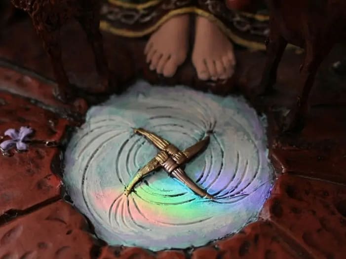 Das Brigid-Kreuz - Schutz und Segen für das Jahr Goldenfarbenes Brigid-Kreuz mit Statue im Hintergrund