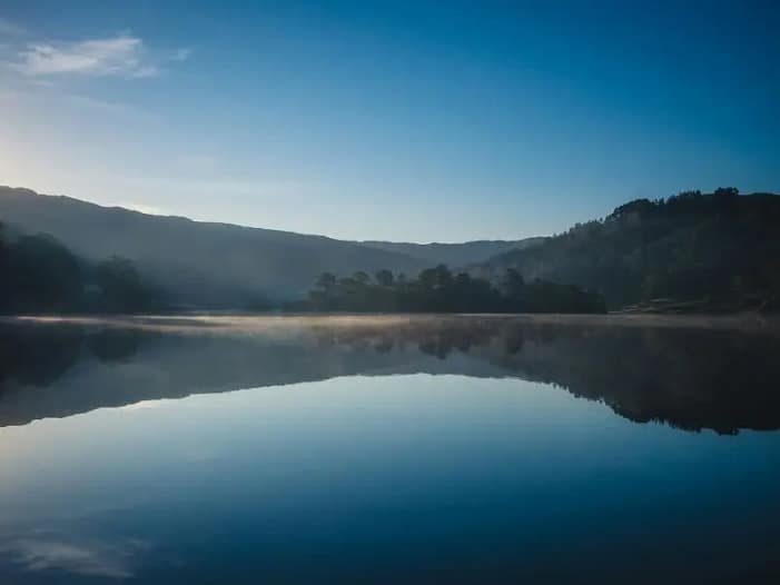 Stiller Bergsee im Morgennebel - innere Verbindung und Selbstbestimmung Spiegelglatter Bergsee im Morgennebel mit Bergspiegelung - Symbol für Stille, innere Verbindung und den Beginn der eigenen Stimme