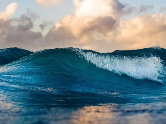 Kraftvolle Welle bricht auf - Symbol für Stimme die sich erhebt Eine kraftvolle blaue Welle bricht im Morgenlicht auf - Symbol für die Stimme die sich erhebt und Wirkung entfaltet
