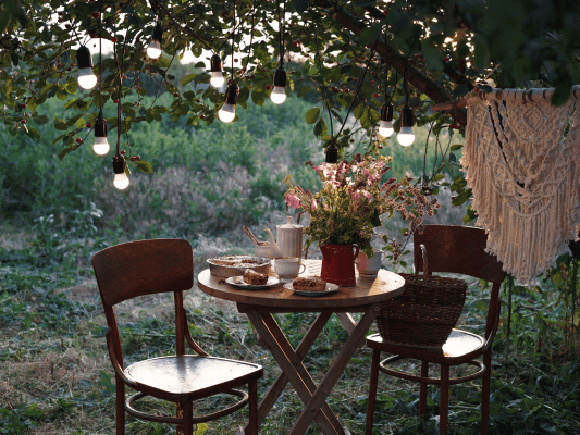 Ein gedeckter Tisch in einem Garten, umgeben von Lichtern - Sinnbild dafür, den Seelengarten im Alltag zu verankern und sich immer wieder mit innerer Fülle zu verbinden