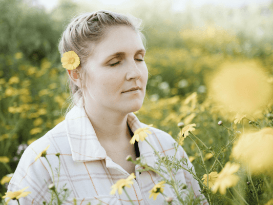 Frau mit Blüte im Haar schaut in warmes Licht, symbolisch für die Vorbereitung auf eine innere Reise