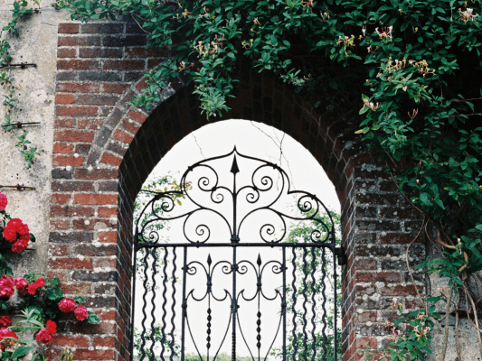 Ein kunstvoll verziertes Tor öffnet sich unter einem alten Backsteinbogen – als würde es Dich einladen, den Weg zu Dir selbst zu gehen und dort innere Ruhe zu finden
