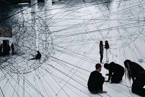 Menschen schaffen künstlerisch Netzwerk aus Fäden